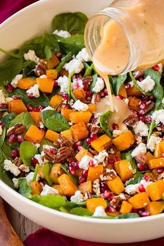 a salad with spinach, carrots and feta cheese being poured into it