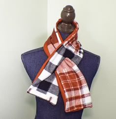 an orange and white plaid scarf on top of a mannequin