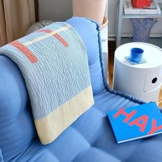 a blue couch sitting next to a white table with a book on top of it