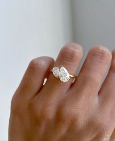 a woman's hand with a diamond ring on top of her finger, and the other hand holding an engagement ring