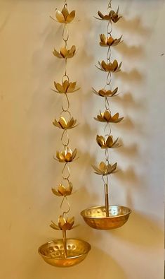 two metal bowls with flowers hanging from the sides and one has a plant in it