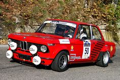 an old red race car driving down the road with its number on it's side