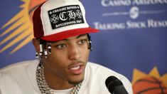 a young man wearing a red and white hat while sitting in front of a microphone