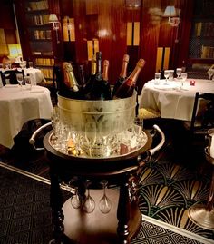 a table with wine bottles and glasses in a bucket on top of a metal stand