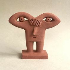 a clay sculpture of a face with two hands on it's head and one eye open