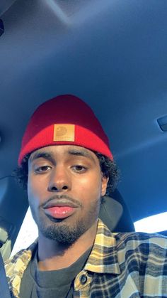 a man wearing a red beanie in the back seat of a car