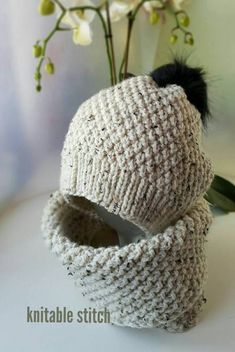 a knitted hat with a black pom - pom attached to it