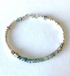 Dainty sparkling Karen Hill Tribe fine silver beaded bracelet with natural blue green moss aquamarine gemstones accented with larger Thai Fine Silver beads. AAA shaded ombré faceted moss Aquamarine rondelles are approximately 4mm. Gemstone bar is 1 1/2 inches and accented with larger flower stamped Thai fine silver beads. Thai fine silver is handmade in northern Thailand by the Karen Hill Tribe people using .997-.999 pure silver. Beautiful lasting luster that rivals sterling silver. Faceted 2.5 Bohemian Silver Faceted Beaded Bracelets, Aquamarine Gemstone Beaded Bracelets, Silver Rondelle Gemstone Beaded Bracelets, Silver Beaded Bracelets For Healing, Healing Silver Beaded Bracelets With Faceted Beads, Silver Rondelle Crystal Bracelet With Gemstone Beads, Silver Crystal Bracelet With Rondelle Gemstone Beads, Silver Crystal Bracelet With Gemstone Beads, Paris Charm Bracelet