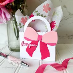 a pink ribbon is tied around a small gift bag with the word happy on it