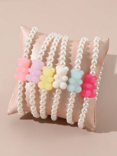 a bunch of bracelets sitting on top of a pillow next to a pink wall