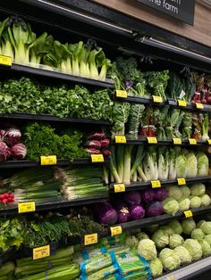 an assortment of vegetables are on display in a grocery store's produce section, including lettuce, broccoli, cabbage and radishes