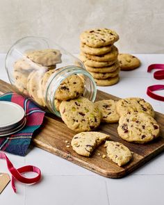 chocolate chip cookies on a cutting board next to a jar of milk and red ribbon