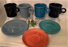 four different colored plates and cups on a table