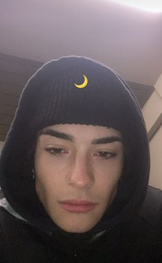 a young man wearing a black hoodie with a crescent moon on the top of it