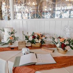 the table is set up for a wedding reception with flowers and an open book on it