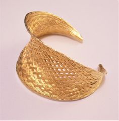 Basket weaved high end luxury strand bracelet bangle cuff vintage gilded gold tone satin smooth bright metal finish open end graduated band golden braided rimmed edge. In excellent never worn vintage condition. Fits most average wrist has a small amount of stretch to the band. Measures 6 inches from end to end, 1 1/2 inches at the widest area of the band and 2 1/2 inches inside. Gold Woven Bracelet Jewelry, Adjustable Gold Woven Bracelet, Adjustable Woven Gold Bracelets, Elegant Adjustable Woven Bracelets, Gold Cuff Bangle For Evening, Elegant Woven Adjustable Bracelets, Adjustable Woven Gold Jewelry, Adjustable Metal Bangle For Evening, Adjustable Metal Evening Bangle