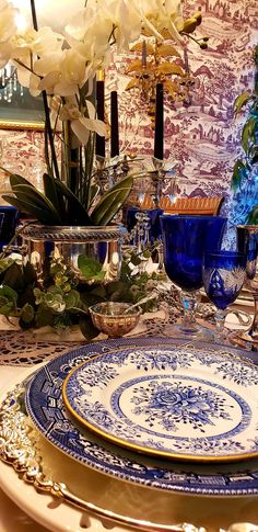 a blue and white plate sitting on top of a table next to a vase filled with flowers