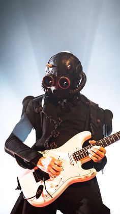 a man in gas mask playing an electric guitar