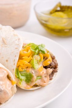 two burritos on a white plate with sauce and lettuce