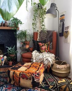 a living room with plants and rugs on the floor next to a fire place