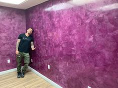 a man standing next to a purple wall