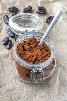 a jar filled with cocoa powder next to some raisins on a piece of paper