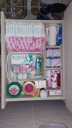 an organized drawer with toiletries and personal care items in the bottom shelf, on top of a tiled floor