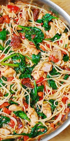 a pan filled with pasta and vegetables on top of a wooden table