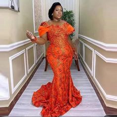 a woman in an orange dress is standing on the floor with her hands out and looking at the camera