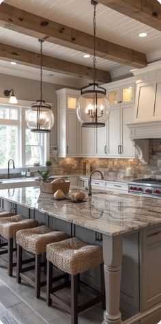 a large kitchen with marble counter tops and stools in front of an island that has four lights hanging from the ceiling