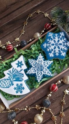 two decorated cookies are in a box on the floor next to christmas ornaments and decorations