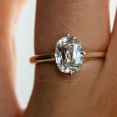 a woman's hand holding an engagement ring with a large diamond