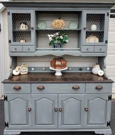 an old china cabinet painted gray with white pumpkins