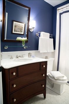 a white toilet sitting next to a bathroom sink under a mirror and a shower curtain