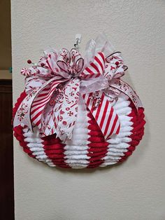 a red and white christmas wreath hanging on the side of a wall with candy canes