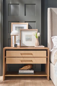 a bedroom with a bed, nightstand and framed pictures on the side table next to it