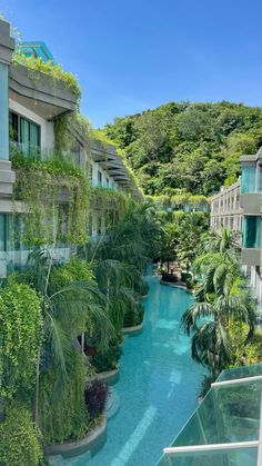 an outdoor swimming pool surrounded by greenery and apartment buildings with balconies on either side