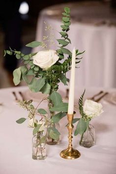 there are two vases with flowers and candles on the table