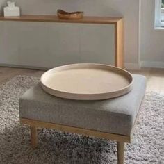 a bowl sitting on top of a ottoman in a living room