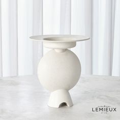 a white vase sitting on top of a table