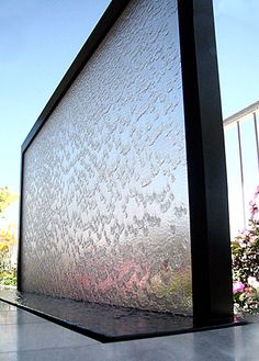 a large glass window sitting on the side of a building next to a flower garden