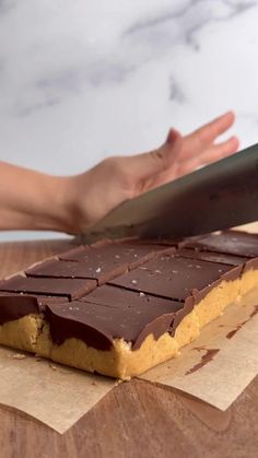 someone is cutting into a chocolate bar with a large knife on it's side