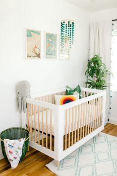 a white crib in the corner of a room next to a potted plant