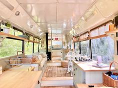 the inside of a bus with lots of windows and wood flooring, including an open kitchen area