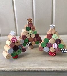 three wine cork christmas trees sitting on top of a wooden table next to each other