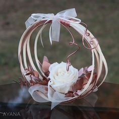 a white rose in a wire wreath on top of a table