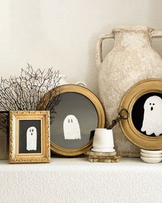 there are three framed pictures on the mantle with ghost decorations in front of them, and one has a spooky face