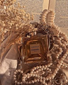 a chanel bottle surrounded by pearls and flowers