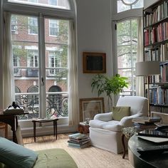 a living room filled with lots of furniture and bookshelves next to large windows