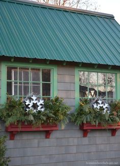 three window boxes with plants in them on the side of a gray building and green roof